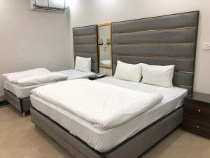 two beds in a hotel room with white sheets at Hotel Five Season Lahore in Lahore