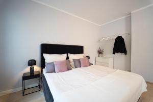 sypialnia z białym łóżkiem z różowymi i fioletowymi poduszkami w obiekcie Charles & Kätchen living Gohlis w Lipsku