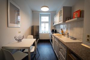 una cocina con fregadero y mesa. en Charles & Kätchen living Gohlis, en Leipzig