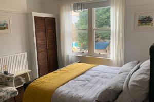Schlafzimmer mit einem Bett vor einem Fenster in der Unterkunft Lovely 4 bedroom home, stones throw from the beach in Brighton & Hove