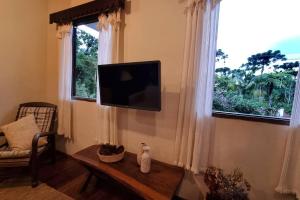 sala de estar con TV de pantalla plana en la pared en Chalé Pedra do índio - no coração de Maringá MG, en Bocaina de Minas