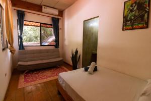 Hostel Villa Vento Surf في سانتا كاتالينا: غرفة نوم بسرير ونافذة واريكة