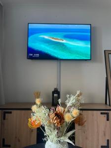 una TV a schermo piatto su un muro con un vaso di fiori di BY NEPTUNE - la Palme Riviera Beach and Pool view a Cannes