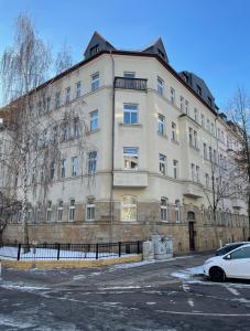 een witte auto geparkeerd voor een gebouw bij Charles & Kätchen living Gohlis in Leipzig