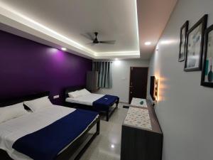 a bedroom with two beds and a purple wall at Sadafuli Guest House Assagao in Assagao