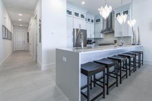 a kitchen with white cabinets and a bar with stools at Wait'n on Sundown in Destin