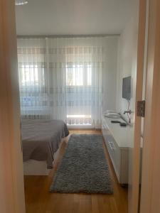 a bedroom with a bed and a desk with a television at MANHATTAN APARTMAN Belvil in Belgrade