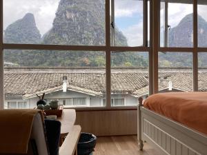 a bedroom with a large window with a mountain view at Lazzy inn in Yangshuo