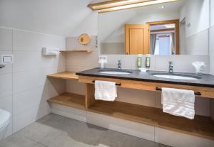 a bathroom with two sinks and a mirror at Hotel Häuserl im Wald in Mariapfarr +51 photos