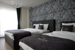 a hotel room with two beds and a wall at Vetus Hotel in Pristina