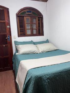 a bedroom with a bed with a window and a door at Casa de Alice in Búzios