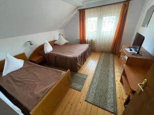 a hotel room with two beds and a television at Pensiunea Genţiana in Vatra Dornei