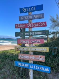 a wooden sign with many signs on the beach at Casa Colorida Búzios in Búzios