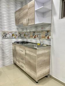 una cocina con armarios de madera y fregadero en Acogedor Apartamento Cercano al Aeropuerto Ernesto Cortissoz en Malambo