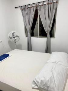 1 dormitorio con cama blanca y ventana en Acogedor Apartamento Cercano al Aeropuerto Ernesto Cortissoz, en Malambo