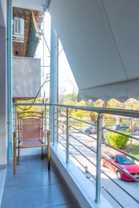 a chair on a balcony with a view of a street at Academia apartments by the park in Athens