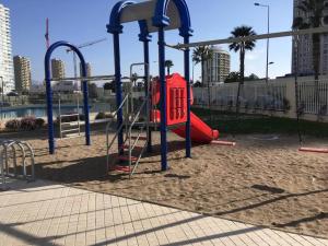 a playground with a red slide in the sand at Amplio dpto a pasos de la playa. in Coquimbo