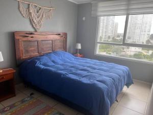 a bedroom with a large blue bed with a window at Amplio dpto a pasos de la playa. in Coquimbo