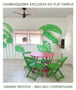 a table and chairs in a room with a plant at Chalés Sununga Flats a 1 minuto da praia in Ubatuba