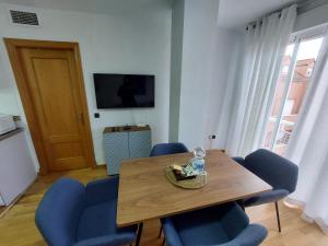 a dining room with a wooden table and blue chairs at APARTAMENTO PLAZA DEL AYUNTAMIENTO con PARKING in Linares