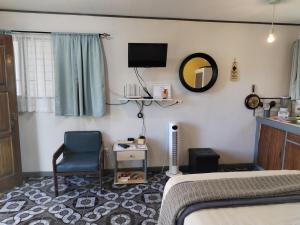 a bedroom with a bed and a chair and a tv at blanc haus in Grecia