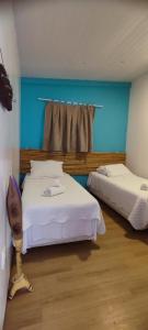 2 Betten in einem Zimmer mit blauer Wand in der Unterkunft Vida de Ilha in Fernando de Noronha