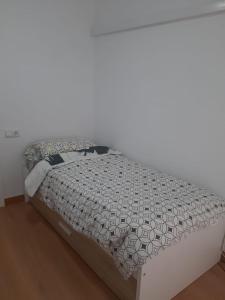 uma cama num quarto com uma parede branca em Las Flores em Múrcia
