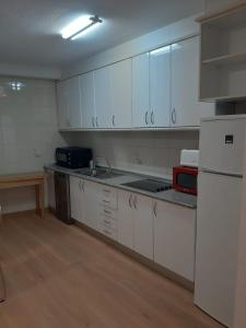 a kitchen with white cabinets and a white refrigerator at Las Flores in Murcia