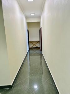 an empty hallway with white walls and a green tile floor at Oceans-Opulence/3BR-5 BEDS in Dar es Salaam