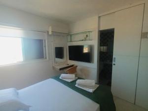 a bedroom with a white bed and a television at Dentro da praia in Fortaleza
