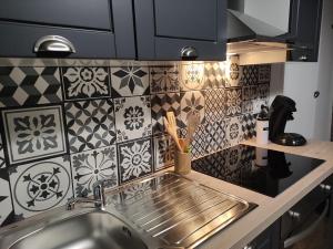 uma cozinha com um lavatório e uma parede de azulejos em Bienvenue chez Coco em Dunkerque
