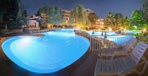 Vita Park Hotel & Aqua Park في البينا: مسبح كبير وكراسي الصالة حوله في الليل