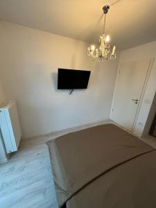 een woonkamer met een televisie en een kroonluchter bij Royal Apartament in Braşov