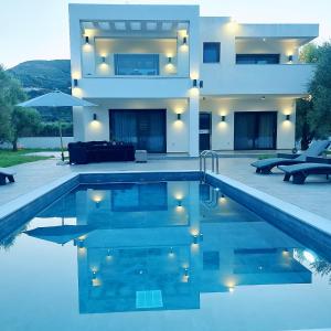 una casa con piscina frente a una casa en Grande Amore Villa, en Pandokrátor
