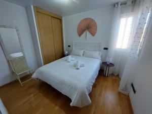 a bedroom with a white bed with two candles on it at Apartamento CentroLinares Con Parking in Linares