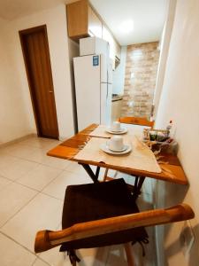 een kleine keuken met een houten tafel en een koelkast bij kitnet Praia do Morro Guarapari in Guarapari