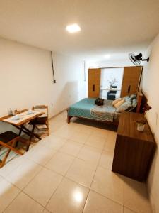 a bedroom with a bed and a table in a room at kitnet Praia do Morro Guarapari in Guarapari