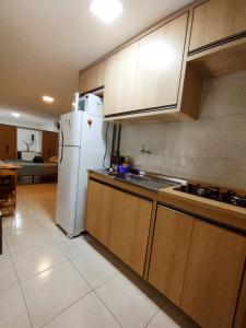 a kitchen with a white refrigerator and wooden cabinets at kitnet Praia do Morro Guarapari in Guarapari