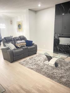 sala de estar con sofá de cuero y mesa de cristal en Beautiful 3 bedroom home, en Calgary