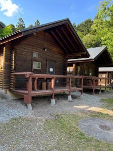 Nasu Takahara Auto Campsite - Vacation STAY 42065v في ناسوشيوبارا: كابينة خشب أمامها مقاعد