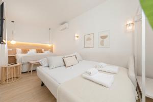 Habitación blanca con 2 camas y sofá en Indulge Faustino 45-3, en Sevilla