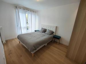 a bed in a white room with a large window at Le clos d'Asnières in Asnières-sur-Seine