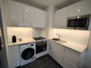 a white kitchen with a washer and a microwave at Le clos d'Asnières in Asnières-sur-Seine