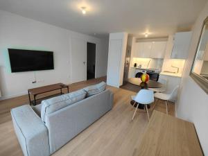 a living room with a couch and a table and a kitchen at Le clos d'Asnières in Asnières-sur-Seine