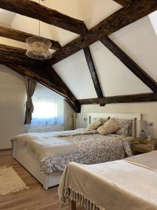 a bedroom with two beds and a ceiling with beams at Mushrooms Malomszállás in Tata