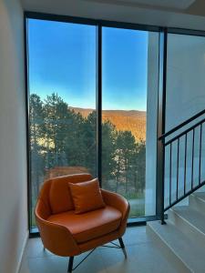an orange chair sitting in front of a large window at Apartman Hera in Vrdnik