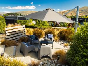 un patio con sillas, una mesa y una sombrilla en Wineberry Lodge, en Wanaka