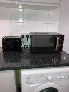 d'un four micro-ondes et d'un grille-pain sur un comptoir de cuisine. dans l'établissement Kingdom Holiday - 12 Hamilton, à Londres