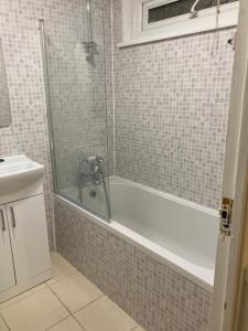 een badkamer met een bad en een wastafel bij Kingdom Holiday - 12 Hamilton in Londen