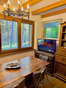 a dining room with a wooden table and a television at Villa Esclusiva a 3 Piani in Bardonecchia